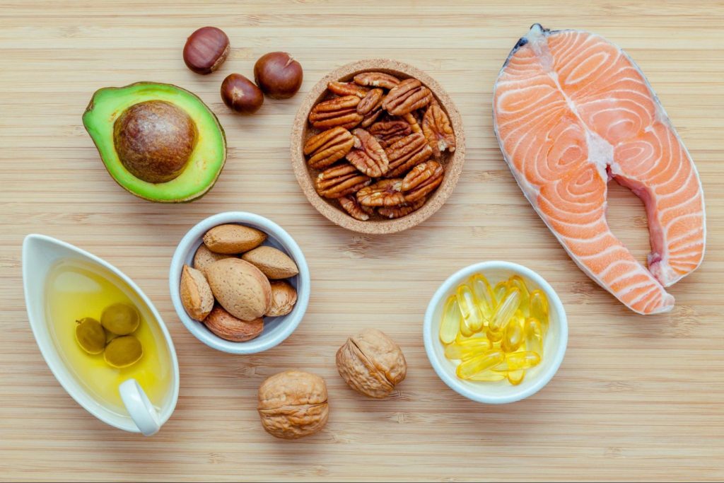 Selection of foods containing polyunsaturated fatty acids such as avocados, nuts, oils, and fish.
