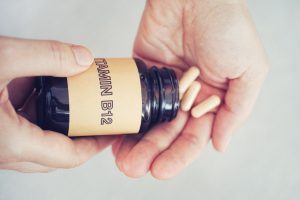Person taking out Vitamin B12 pills out of bottle. Close up.
